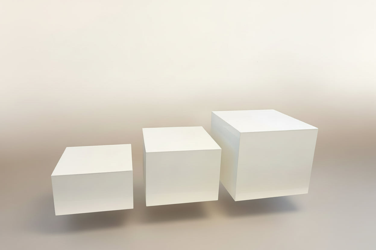 Three white cubes of different sizes on a white platform with a blue background